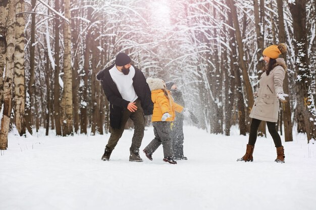 Família feliz brincando e rindo no inverno ao ar livre na neve. dia de inverno do parque da cidade.