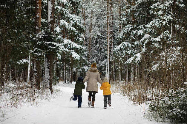 Família feliz brincando e rindo no inverno ao ar livre na neve. dia de inverno do parque da cidade.