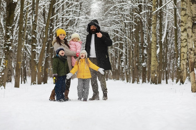 Família feliz brincando e rindo no inverno ao ar livre na neve. Dia de inverno do parque da cidade.