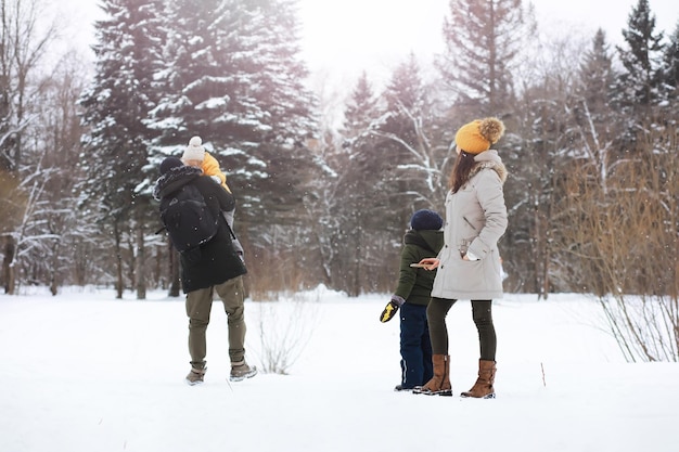 Família feliz brincando e rindo no inverno ao ar livre na neve. Dia de inverno do parque da cidade.