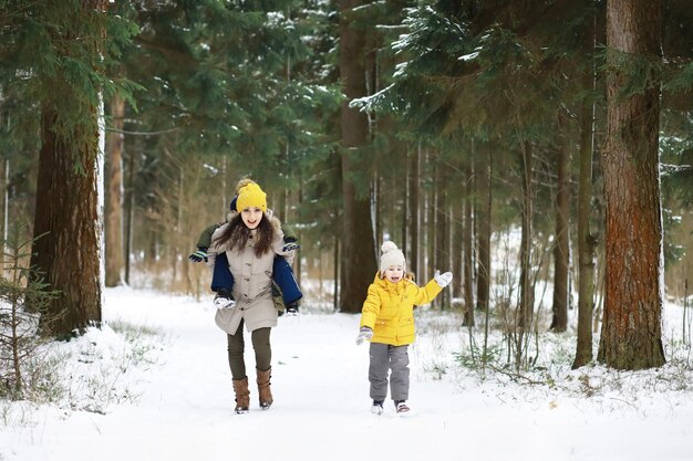 Família feliz brincando e rindo no inverno ao ar livre na neve. dia de inverno do parque da cidade.