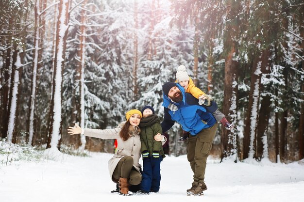 Família feliz brincando e rindo no inverno ao ar livre na neve. Dia de inverno do parque da cidade.