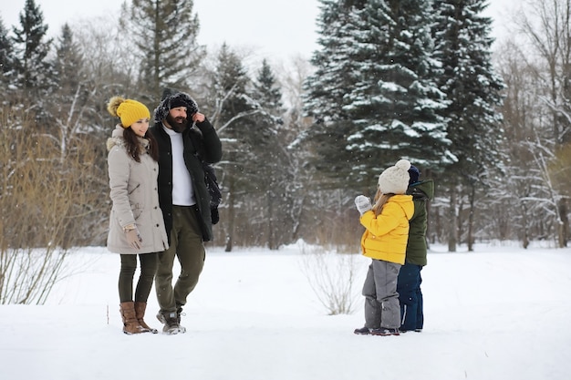 Família feliz brincando e rindo no inverno ao ar livre na neve. Dia de inverno do Parque da cidade.