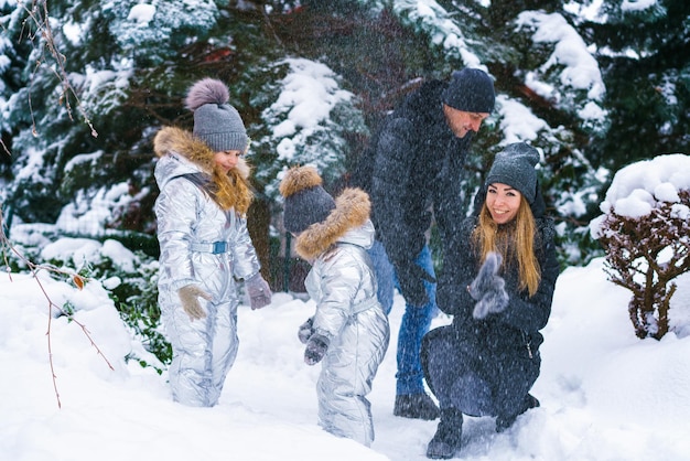 Família feliz brincando e rindo no inverno ao ar livre no parque da cidade de neve dia de inverno no coágulo de inverno ...