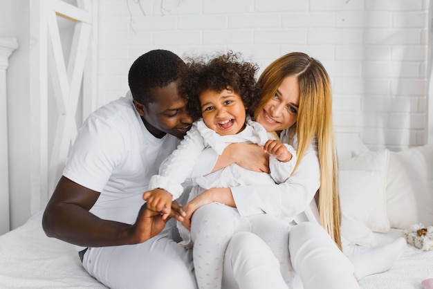 Família feliz brincando na cama com a filha