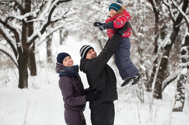 Família feliz brincando na floresta de inverno