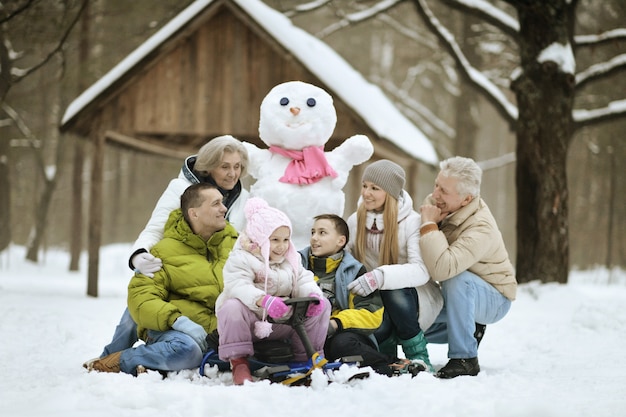 Família feliz brincando na neve fresca e construindo um boneco de neve em um lindo dia ensolarado de inverno ao ar livre na natureza