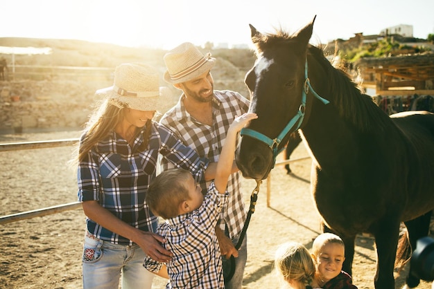 Familia feliz con caballo divirtiéndose en el rancho agrícola Centrarse en los ojos de los animales