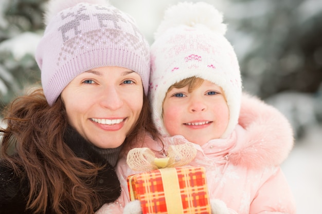 Familia feliz con caja de regalo en invierno al aire libre. Concepto de vacaciones de Navidad