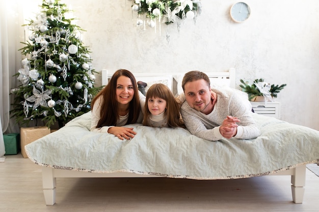 Familia feliz en la cama en casa en un ambiente acogedor