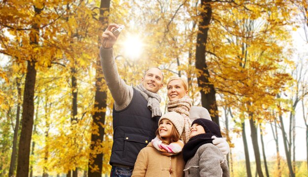 Foto familia feliz con la cámara en el parque de otoño