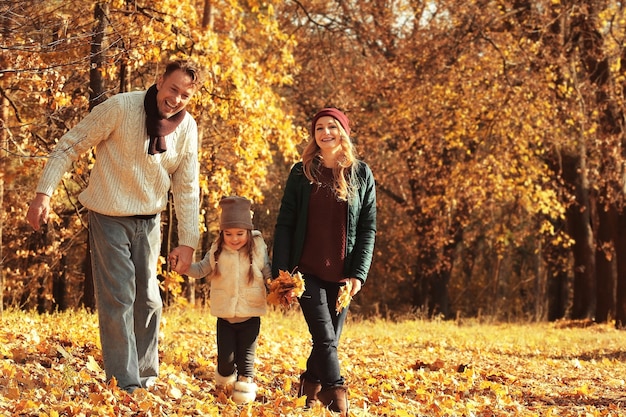 Familia feliz caminando en el hermoso parque otoño