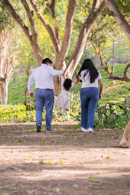 Familia feliz caminando por el parque por la tarde tomados de la mano
