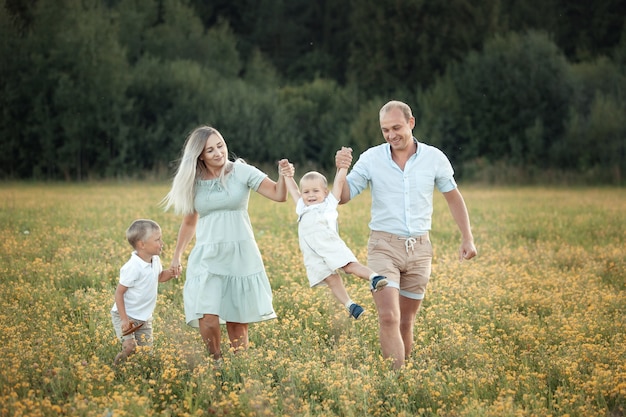 Foto família feliz caminha no campo em diversão de verão ao pôr do sol