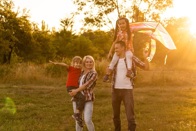 Família feliz caminhando no campo e olhando o pôr do sol