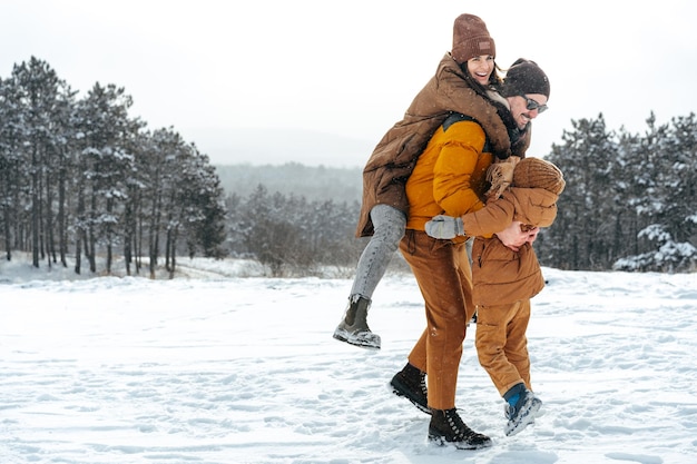 Família feliz caminhando no inverno ao ar livre na neve