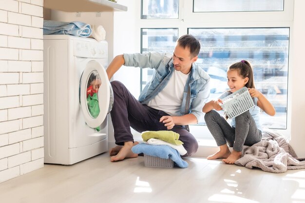 Familia feliz cargando ropa en lavadora en casa