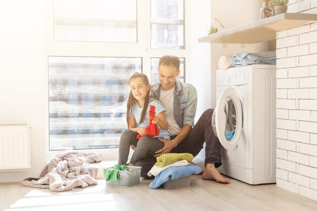 Familia feliz cargando ropa en lavadora en casa