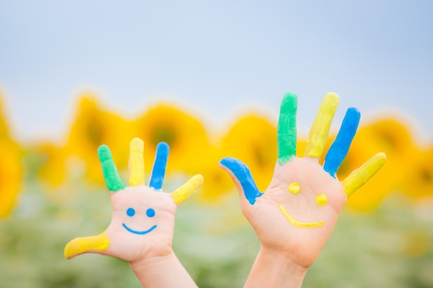 Familia feliz con carita sonriente en las manos contra el cielo azul y el fondo amarillo del girasol