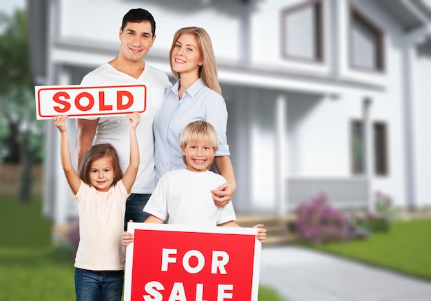 Familia feliz con cartel de venta