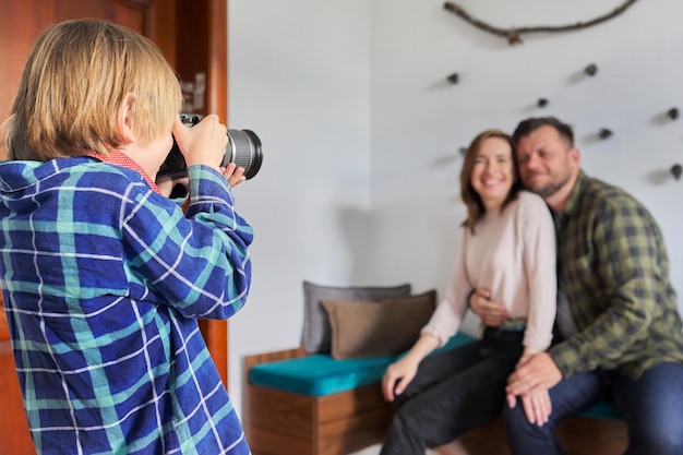 Familia feliz en casa hijo pequeño con cámara tomando fotos de padres abrazados