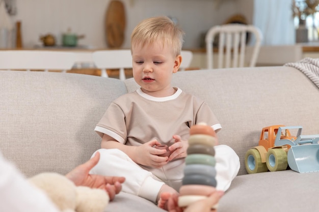 Familia feliz en casa madre y bebé jugando con juguetes en el sofá en casa en el interior pequeño niño c