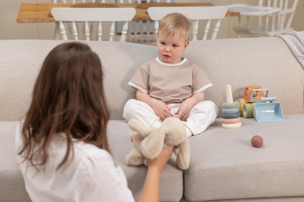 Familia feliz en casa madre y bebé jugando con juguetes en el sofá en casa en el interior pequeño niño c