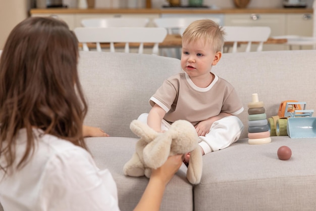 Familia feliz en casa madre y bebé jugando con juguetes en el sofá en casa en el interior pequeño niño c