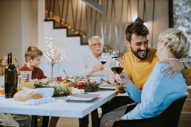 Familia feliz cenando con vino tinto en casa