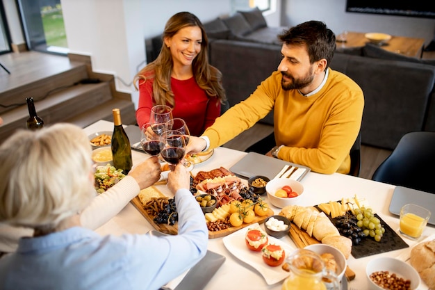 Familia feliz cenando con vino tinto en casa