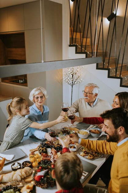 Familia feliz cenando con vino tinto en casa