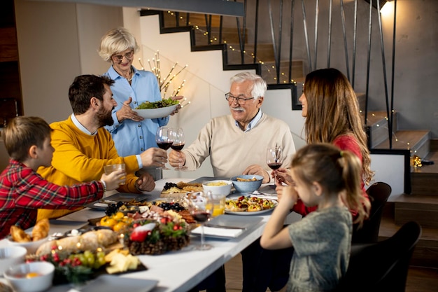 Familia feliz cenando con vino tinto en casa