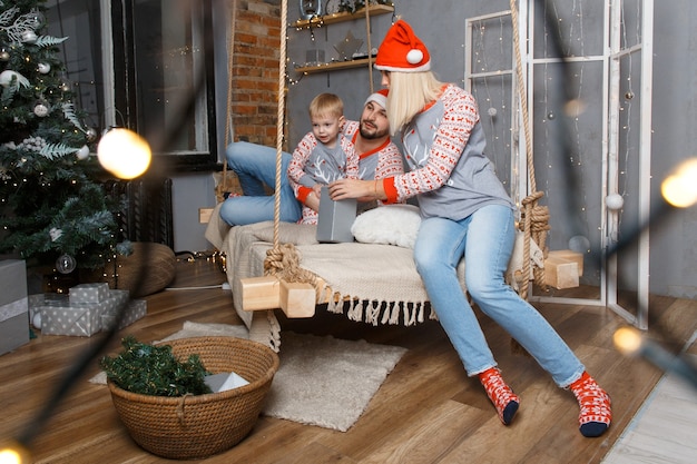 Familia feliz cerca del árbol de Navidad en el dormitorio.