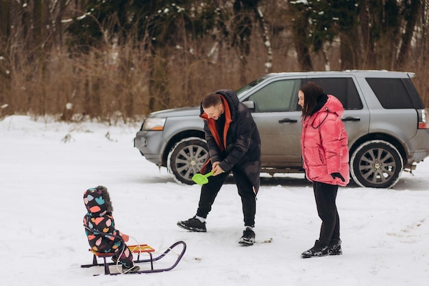 Familia feliz cerca del coche en el bosque el día de invierno