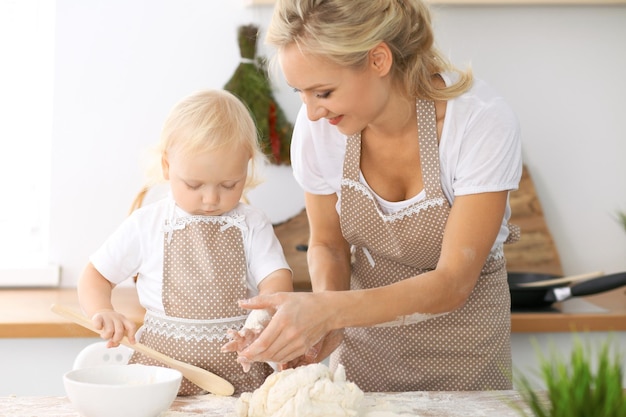 Familia feliz en la cocina. Madre e hija cocinando pastel de vacaciones o galletas para el día de la madre, serie de fotos de estilo de vida informal en el interior de la vida real