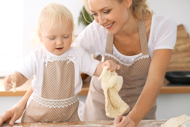 Familia feliz en la cocina. Madre e hija cocinando pastel de vacaciones o galletas para el día de la madre, serie de fotos de estilo de vida informal en el interior de la vida real