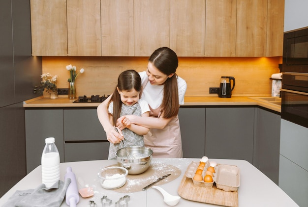 Familia feliz en la cocina, madre e hija preparan masa para hornear galletas Pastel de Pascua