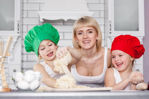 Familia feliz en la cocina. madre e hijos preparando la masa, hornear galletas