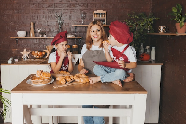 Familia feliz en la cocina. mamá e hijos preparan masa, hornean galletas. día de la Madre.