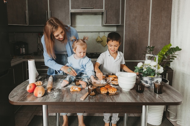 Familia feliz en la cocina. mamá e hijos preparan masa y hornean un pastel para el día de la madre.