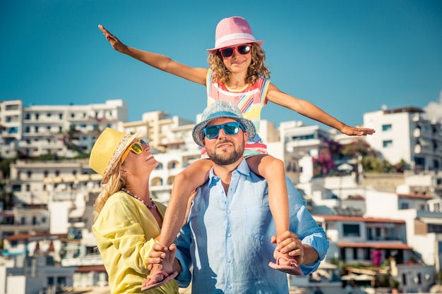 Familia feliz con coloridas gafas de sol y sombreros con una ciudad europea de fondo