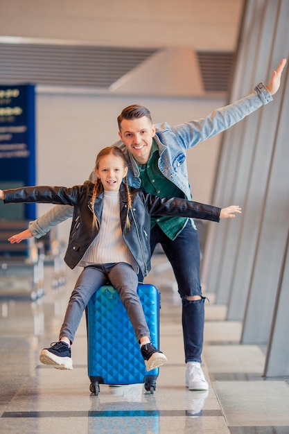 Família feliz com bagagem e cartão de embarque no aeroporto à espera de embarque