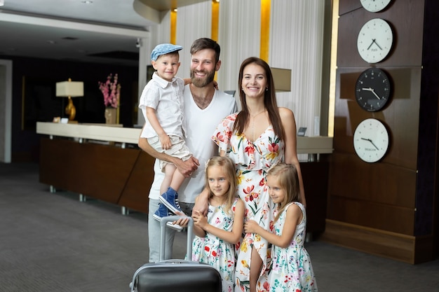 Família feliz com bagagem perto da recepção no hotel.