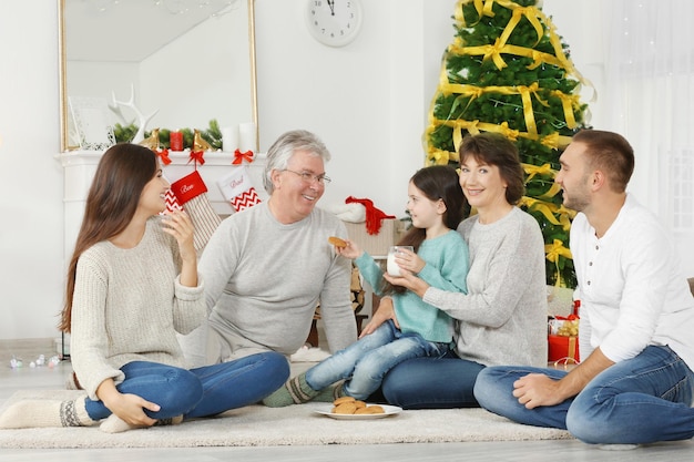 Família feliz com biscoitos e leite na sala decorada para o Natal