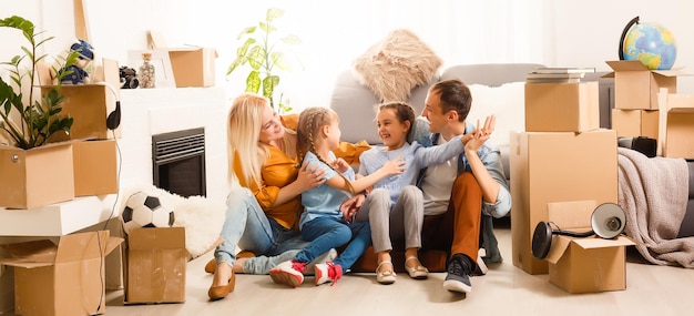 Foto família feliz com caixas de papelão na casa nova no dia da mudança.