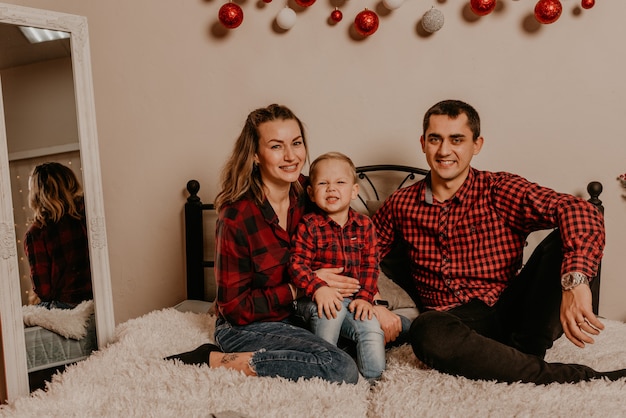 Família feliz com criança comemorando ano novo e natal na árvore de Natal decorada e guirlandas