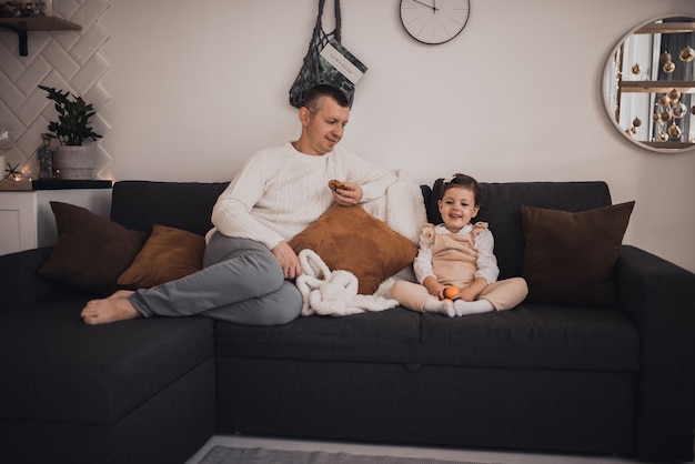 Foto família feliz com criança comemorando ano novo e natal na árvore de natal decorada e guirlandas