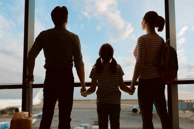 Família feliz com criança no aeroporto Pais e filhos olham pela janela no avião