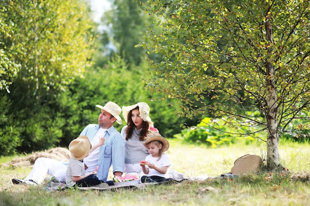 Família feliz com crianças fazendo piquenique no parque pais com crianças sentadas na grama do jardim e comendo melancia ao ar livre