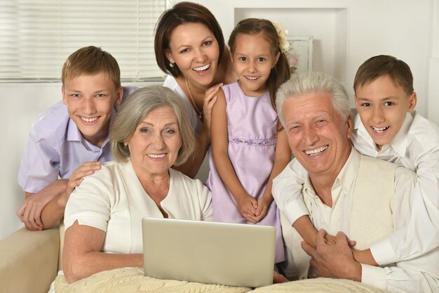 Família feliz com crianças no sofá na sala com laptop